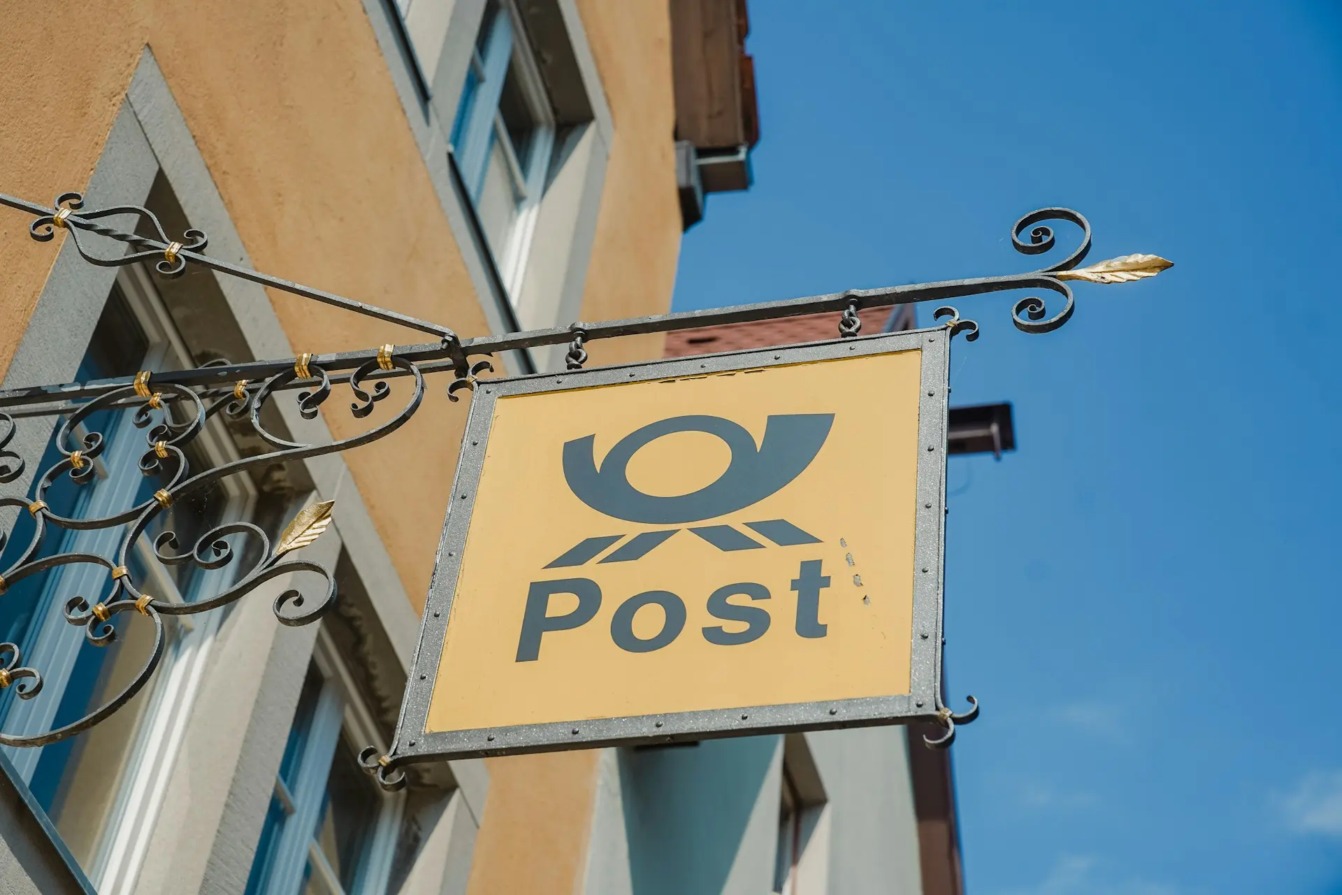 Large mustard yellow and teal sign with the word Post and symbol above it