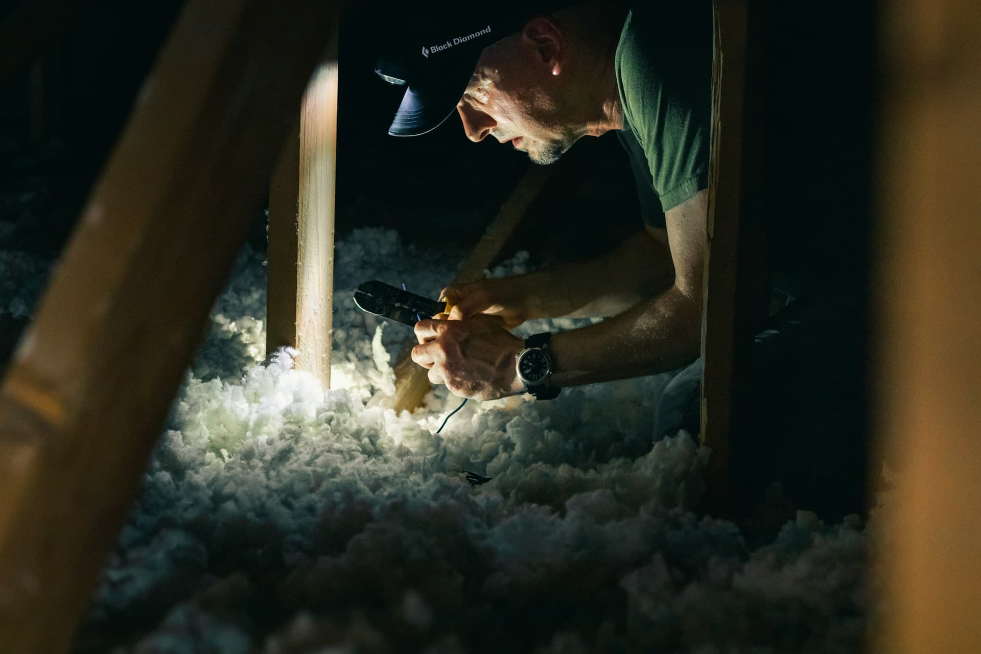 Man working in dark attic of house with headlamp for light source